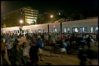 Crowds and light rail on San Carlos Avenue at night, Independence Day. San Jose, California, USA (color)