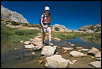 Woman crossing stream on rocks, John Muir Wilderness. California, USA ( color)