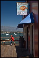 Man eating on wharf next to Fish and Chips restaurant. Santa Barbara, California, USA (color)