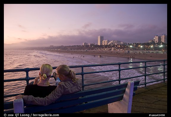 Two women sitting on bench at sunset , Santa Monica Pier. Santa Monica, Los Angeles, California, USA