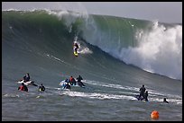Surfer down huge wall of water observed from jet skis. Half Moon Bay, California, USA (color)