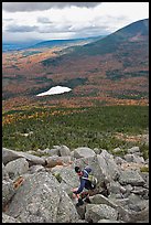 Hiker descends from summit amongst boulders above treeline. Baxter State Park, Maine, USA (color)
