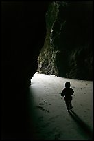 Infant walking towards the light in sea cave. Bandon, Oregon, USA