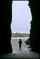 Infant standing at sea cave opening. Bandon, Oregon, USA