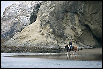 Woman horse-riding on beach next to sea cave entrance. Bandon, Oregon, USA ( color)