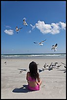 Girl sitting on beach with birds flying, Jetty Park. Cape Canaveral, Florida, USA ( color)