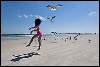 Girl jumping on beach with seagulls flying, Jetty Park. Cape Canaveral, Florida, USA (color)