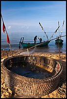 Fishermen pulling net out of circular basket. Phu Quoc Island, Vietnam (color)