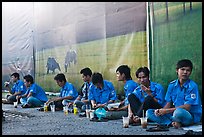 Uniformed students sitting in front of backdrops depicting traditional landscapes. Ho Chi Minh City, Vietnam (color)