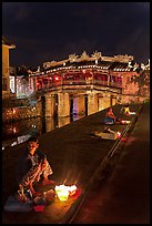 Candle vendors in front of Japanese bridge at night. Hoi An, Vietnam (color)