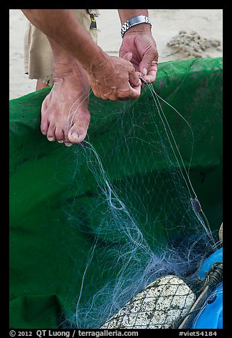 Close-up of hands and feet of man mending net. Da Nang, Vietnam