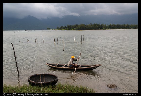 Fisherman rowing canoe in lagoon. Vietnam