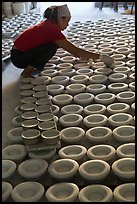 Woman laying ceramic bowls to dry in workshop. Bat Trang, Vietnam (color)