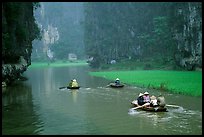 Villagers go to work floating a shallow river in Tam Coc. Ninh Binh,  Vietnam (color)