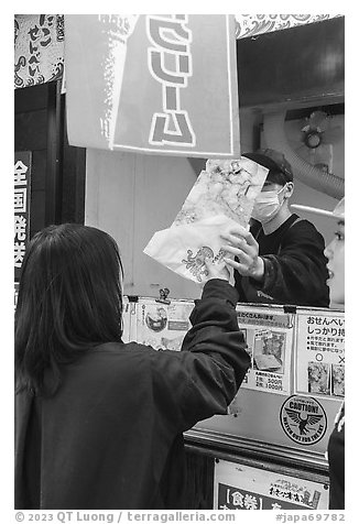 Customer receiving tako senbei octopus cracker. Enoshima Island, Japan (black and white)