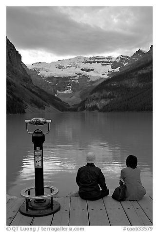 Couple sitting at the edge of Lake Louise at dawn. Banff National Park, Canadian Rockies, Alberta, Canada (black and white)