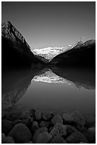 Boulders, Mirror-like Lake Louise and Victoria Peak, early morning. Banff National Park, Canadian Rockies, Alberta, Canada (black and white)