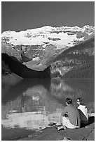 Couple sitting in the sun in front of Lake Louise, morning. Banff National Park, Canadian Rockies, Alberta, Canada (black and white)