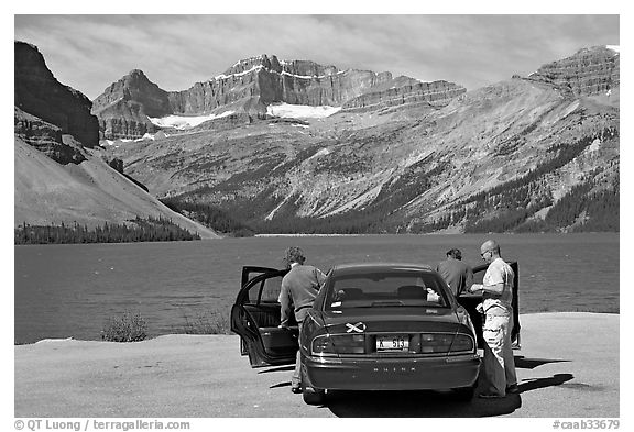 Tourists stepping out of a car next to Bow Lake. Banff National Park, Canadian Rockies, Alberta, Canada (black and white)