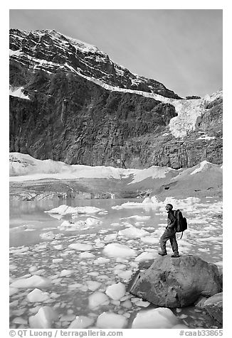 Hiker with backpack looking at iceberg-filed lake, glaciers, and mountain, Mt Edith Cavell. Jasper National Park, Canadian Rockies, Alberta, Canada