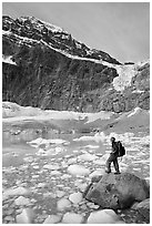 Hiker with backpack looking at iceberg-filed lake, glaciers, and mountain, Mt Edith Cavell. Jasper National Park, Canadian Rockies, Alberta, Canada ( black and white)
