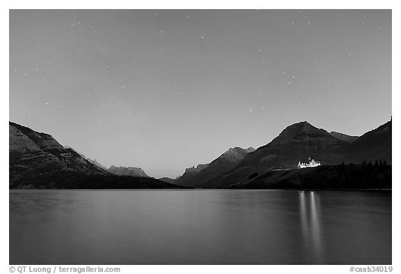 Waterton lake by night with stars in the sky in lights of Price of Wales Hotel. Waterton Lakes National Park, Alberta, Canada (black and white)