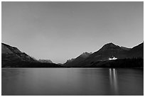 Waterton lake by night with stars in the sky in lights of Price of Wales Hotel. Waterton Lakes National Park, Alberta, Canada ( black and white)