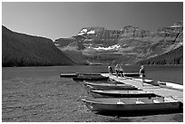 Dock and small boats, with tourists walking down, Cameron Lake. Waterton Lakes National Park, Alberta, Canada ( black and white)