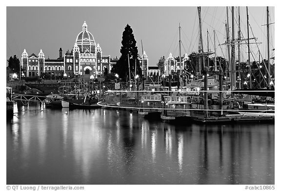 Boats in inner harbor with a trail of lights and parliament building lights. Victoria, British Columbia, Canada