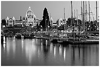 Boats in inner harbor with a trail of lights and parliament building lights. Victoria, British Columbia, Canada ( black and white)