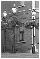 Street lamps with flower baskets and brick wall. Victoria, British Columbia, Canada ( black and white)