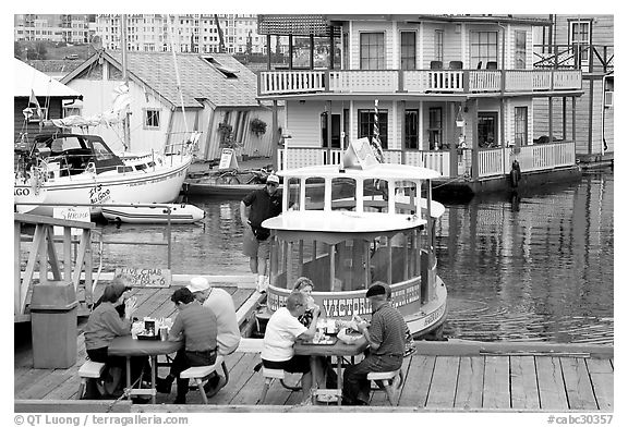 People eating fish and chips on deck,  Fisherman's wharf. Victoria, British Columbia, Canada (black and white)
