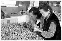 Two elderly women choosing tropical fruit. Vancouver, British Columbia, Canada ( black and white)