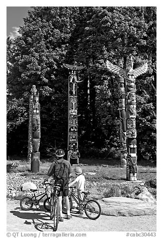 Family with bicycles looking at Totems, Stanley Park. Vancouver, British Columbia, Canada (black and white)