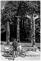 Family with bicycles looking at Totems, Stanley Park. Vancouver, British Columbia, Canada (black and white)