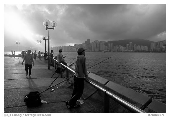 Fishing on the waterfront promenade, sunrise. Hong-Kong, China (black and white)
