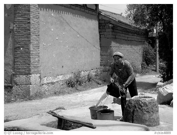 Bai woman fills up a water bucket at the well. Shaping, Yunnan, China