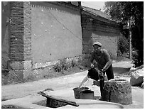 Bai woman fills up a water bucket at the well. Shaping, Yunnan, China (black and white)