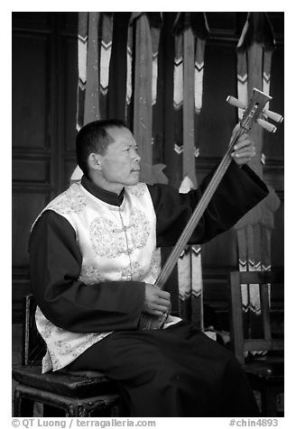 Musician playing a three-stringed traditional moon guitar. Baisha, Yunnan, China