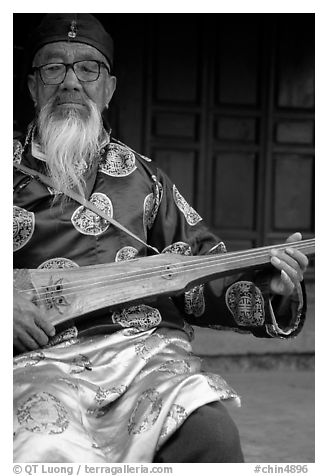 Elderly musician playing the a traditional guitar. Baisha, Yunnan, China