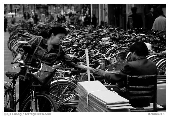 Woman checking out her bicycle at a bicycle lot. Kunming, Yunnan, China (black and white)