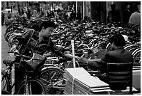 Woman checking out her bicycle at a bicycle lot. Kunming, Yunnan, China ( black and white)