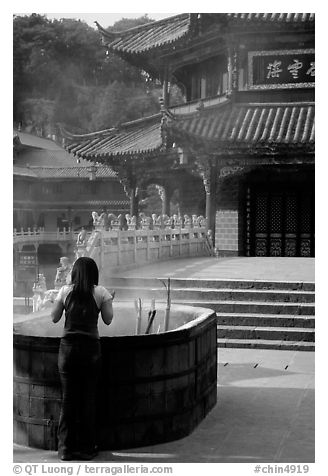 Woman offers incense in the central courtyard of Yantong Si. Kunming, Yunnan, China (black and white)