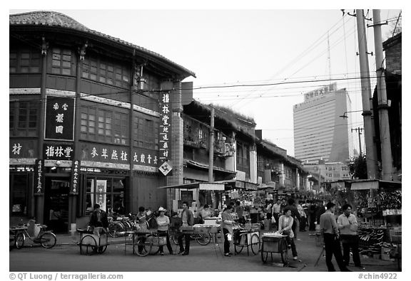 Old wooden buildings, with a high rise in the background. Kunming, Yunnan, China (black and white)