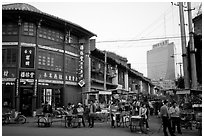 Old wooden buildings, with a high rise in the background. Kunming, Yunnan, China (black and white)