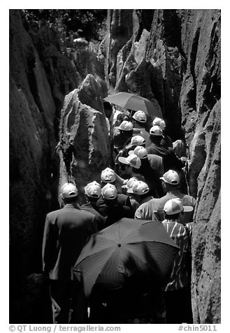 Crowds of Chinese tourists in a walkway among the limestone pillars. Shilin, Yunnan, China (black and white)