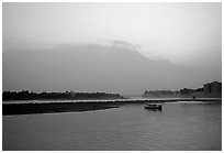 Boat at the confluence of the Dadu He and Min He rivers at sunset. Leshan, Sichuan, China (black and white)