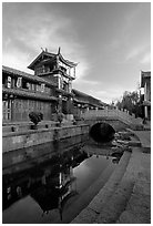 Kegong tower (memorial archway of imperial exam) reflected in canal, sunrise. Lijiang, Yunnan, China (black and white)
