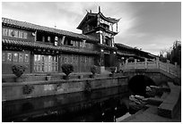 Kegong tower (memorial archway of imperial exam) reflected in canal, sunrise. Lijiang, Yunnan, China (black and white)