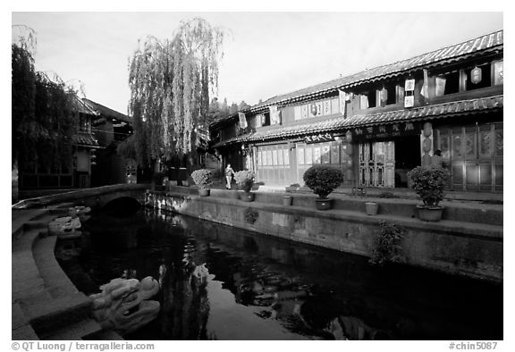 Buildings on Square street reflected in canal, sunrise. Lijiang, Yunnan, China (black and white)